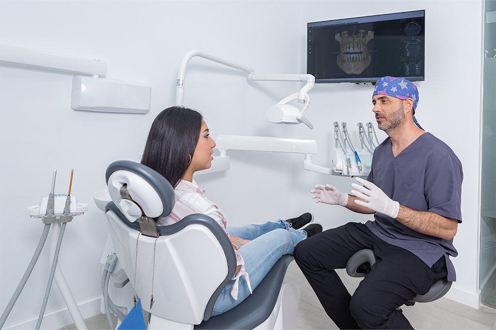 Dental professional reviewing a Teeth-In-A-Day implant treatment model with an adult patient during a consultation in Kingston.
